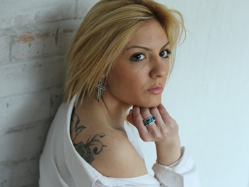 Tattooed model with crosses earrings and turquoise ring